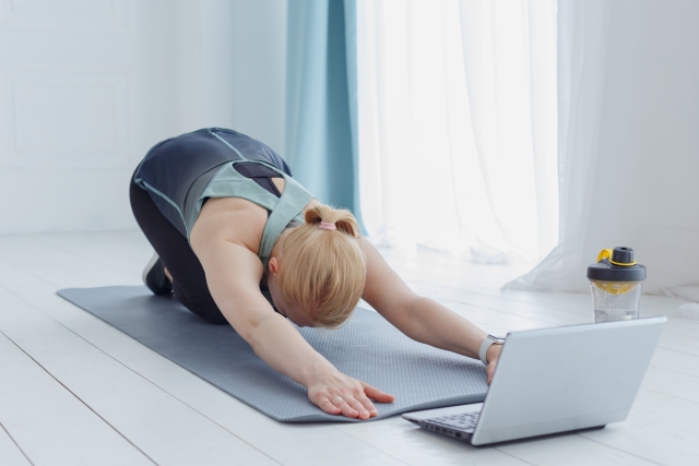 オンラインでヨガのレッスンを受けている女性 オンラインでヨガのレッスンを受けている女性